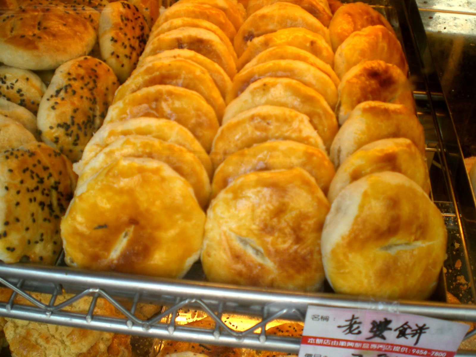 Wife cakes (laopo bing) — golden flaky Cantonese pastries on a bakery shelf