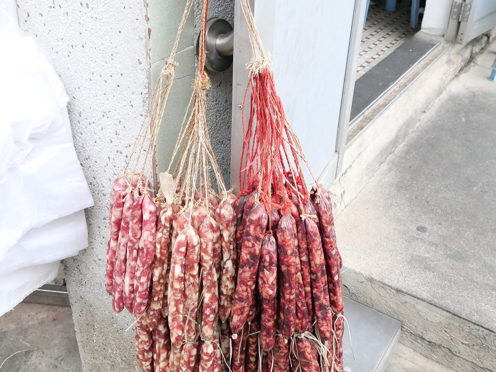 Bundles of Chinese cured sausages hanging outside a shop