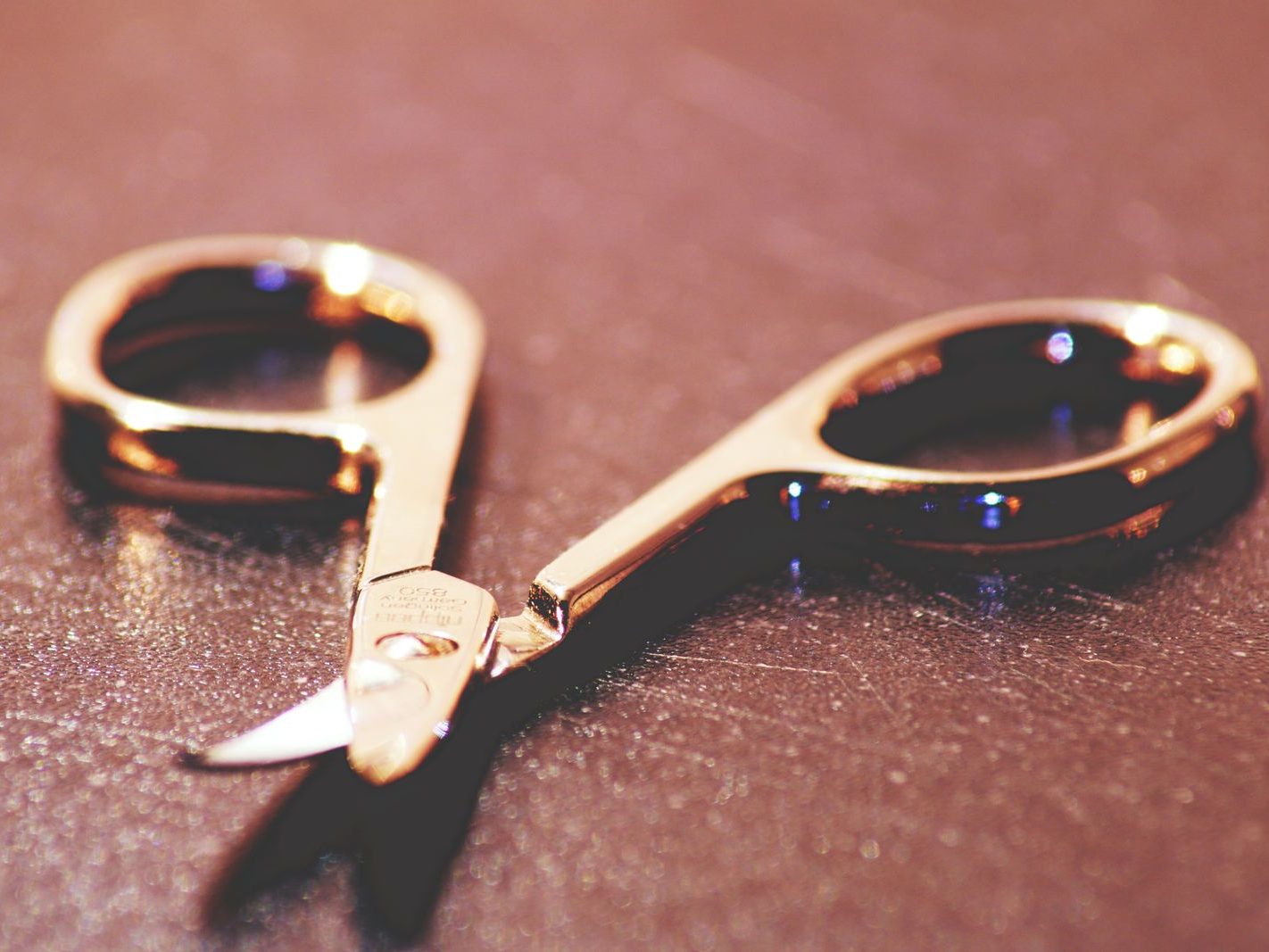 Close-up of gold-colored scissors on a textured surface