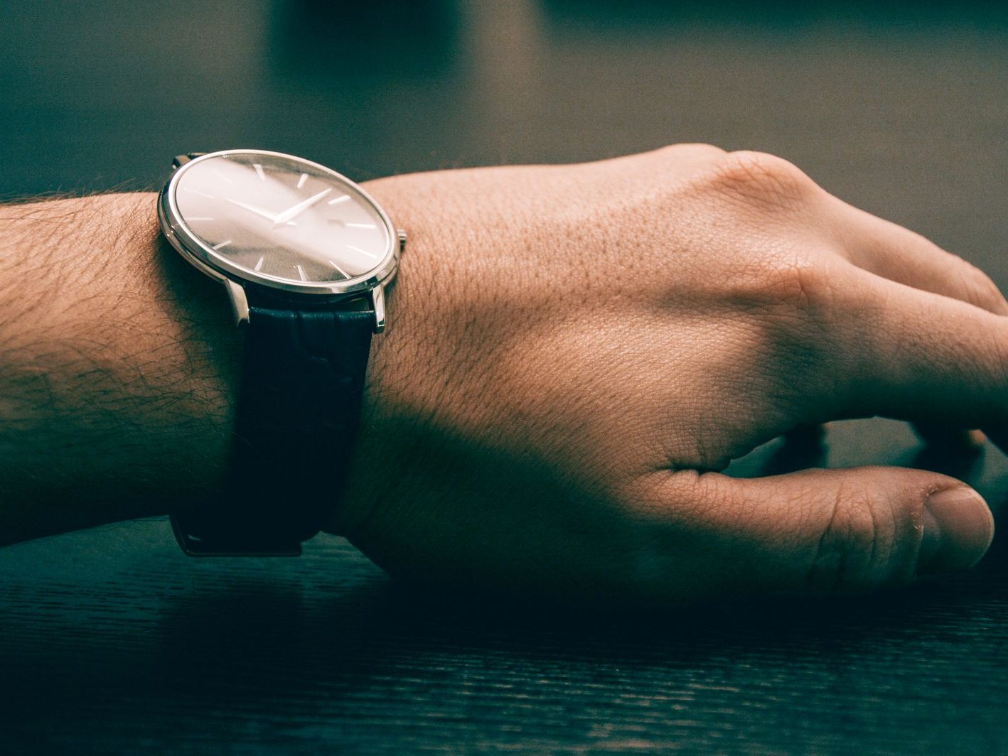 Minimalist analog wristwatch with black leather strap worn on a wrist